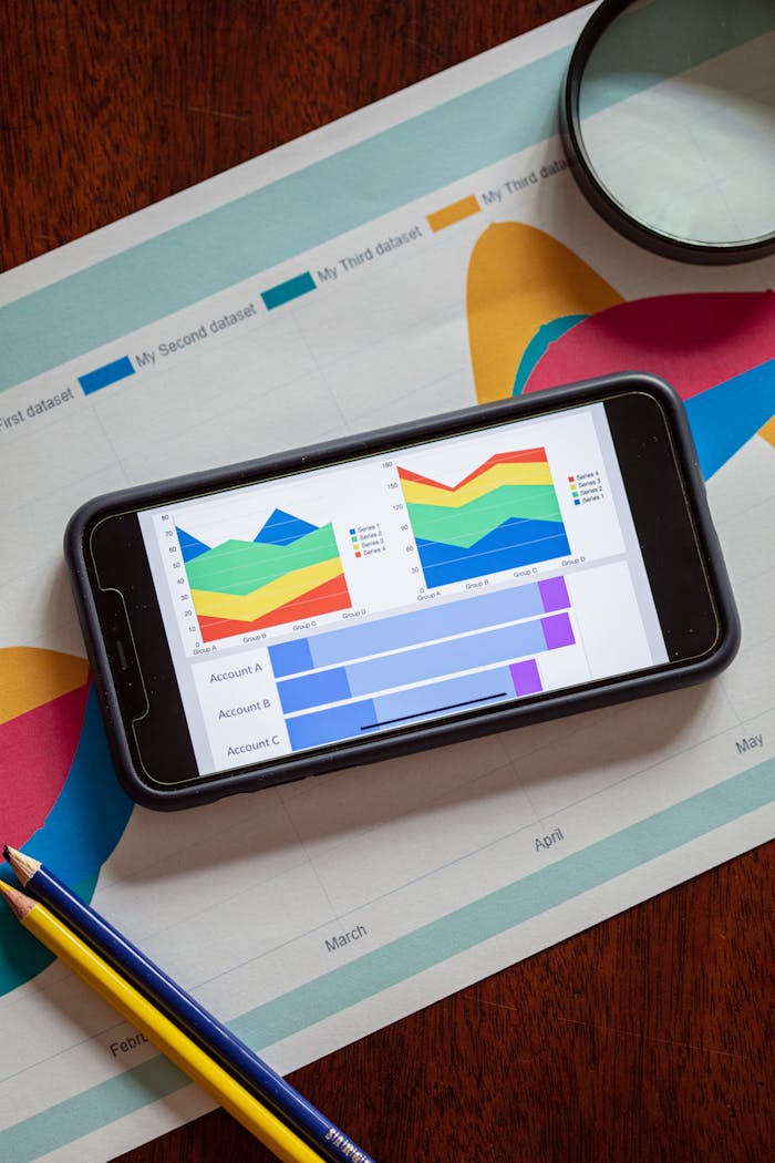 services-02 Smartphone displaying colorful data charts and graphs on a paper report with pencils.